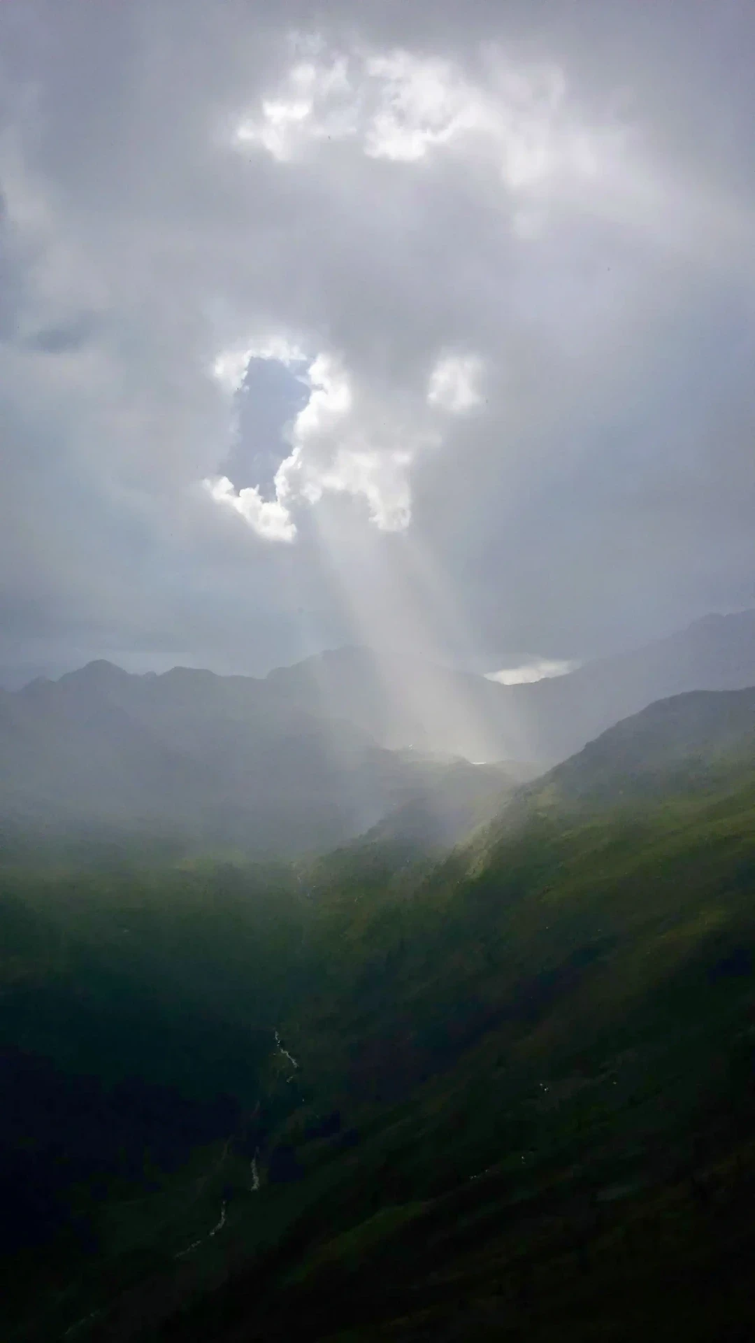 Sonnenstrahlen durchbrechen Wolken über einer Berglandschaft